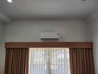 Modern living room with air conditioning and large window with curtains