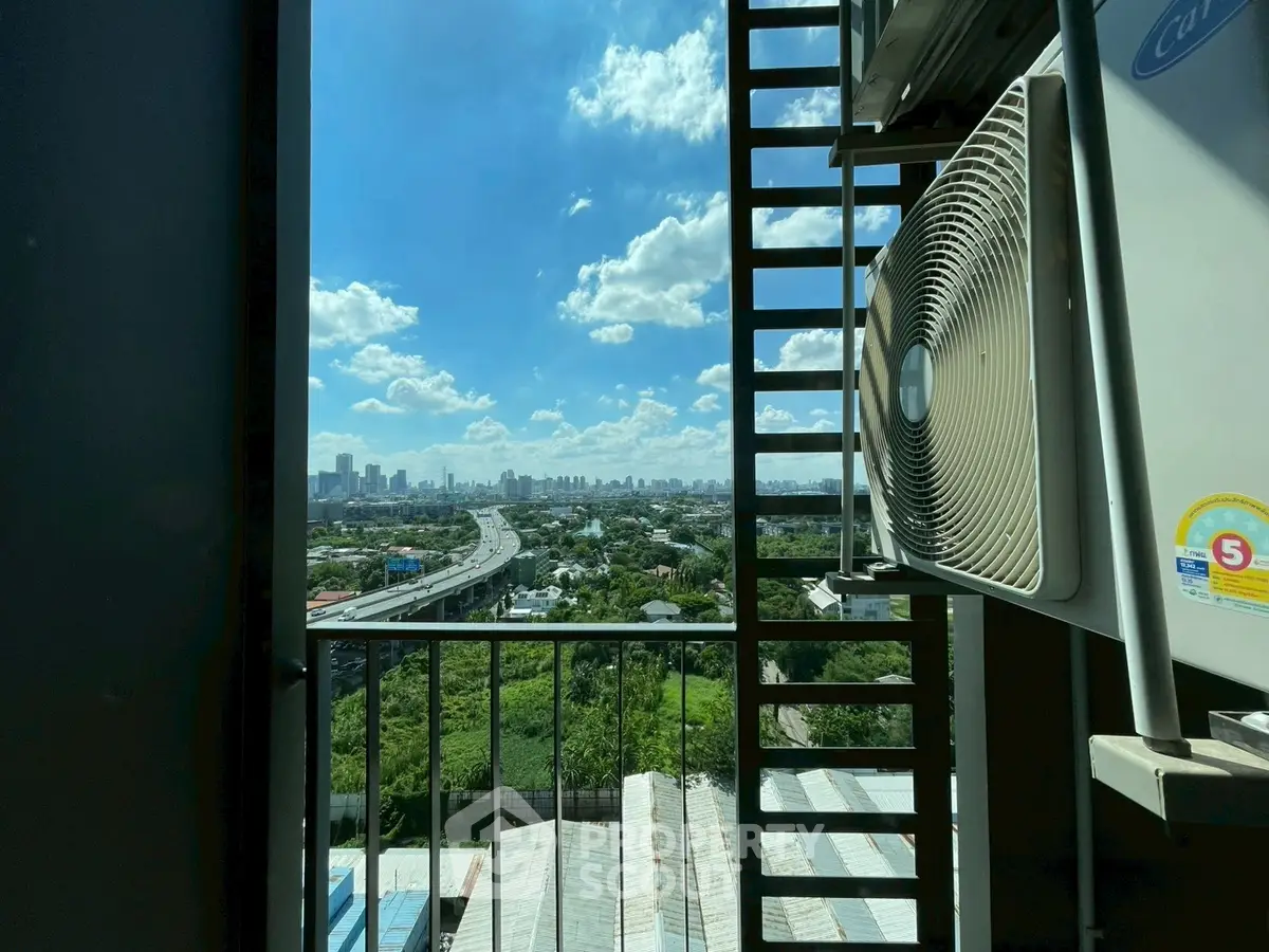 Stunning cityscape view from a high-rise balcony with clear blue skies and lush greenery.