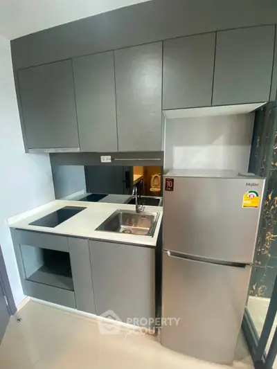 Modern compact kitchen with sleek cabinetry and stainless steel appliances in a stylish apartment.