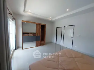 Spacious bedroom with modern wardrobe and large window for natural light.