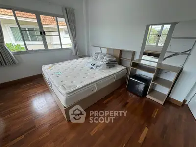 Spacious bedroom with wooden flooring and large window for natural light