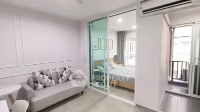 Modern apartment interior with cozy living room and bedroom separated by glass doors.