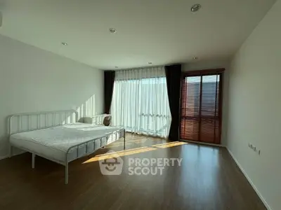 Spacious bedroom with large windows and wooden flooring, perfect for natural light lovers.