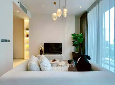 Modern living room with elegant decor and large windows offering natural light.