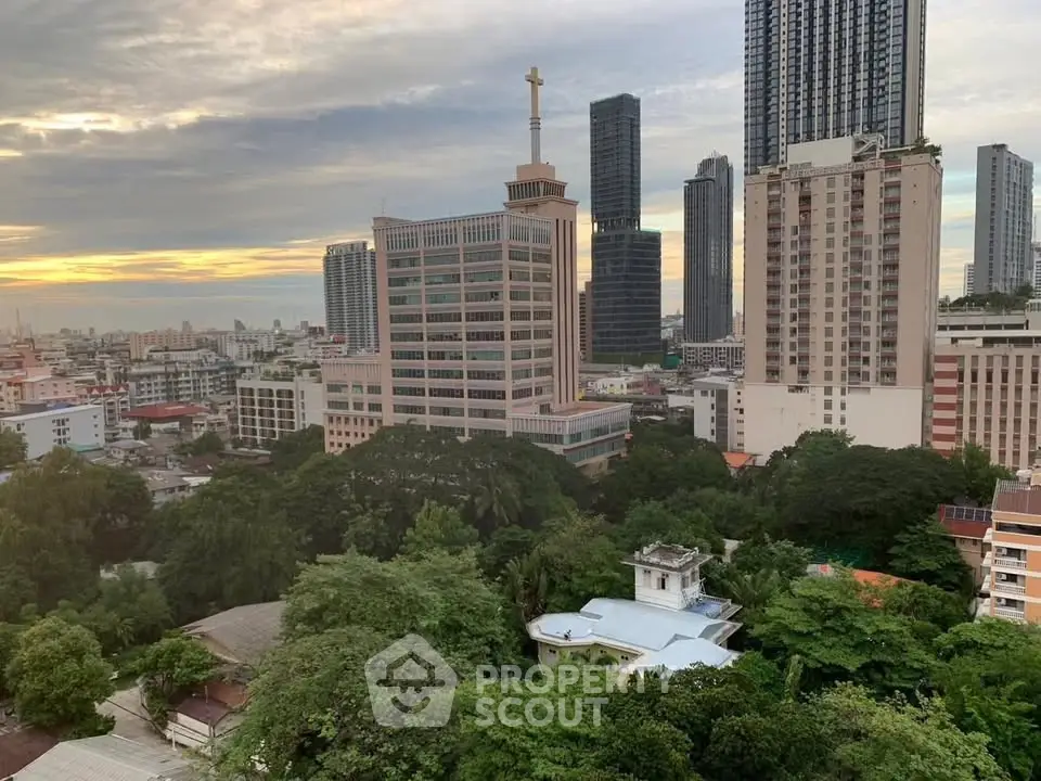 Stunning cityscape view with lush greenery and modern high-rise buildings at sunset.