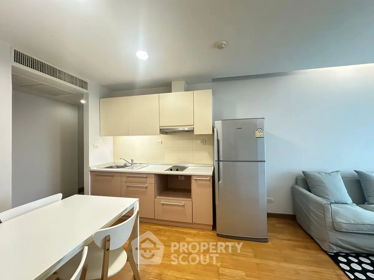 Modern kitchen with sleek cabinetry and stainless steel fridge in open-plan living area.