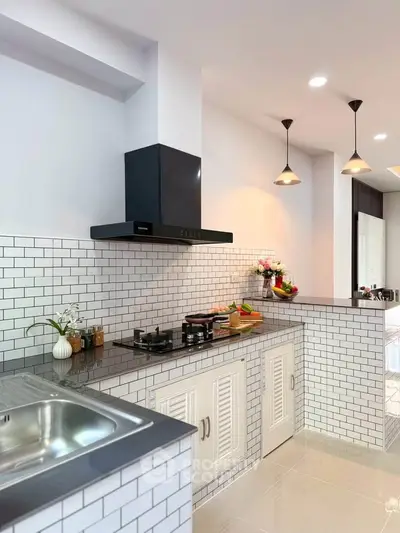 Modern kitchen with sleek design, featuring a gas stove and stylish lighting.