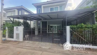 Modern two-story house with covered carport and gated entrance in suburban neighborhood.