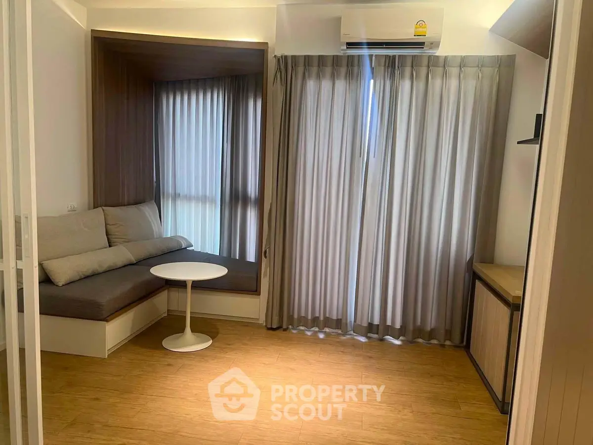 Modern living room with cozy seating and natural light, featuring elegant curtains and wooden flooring.