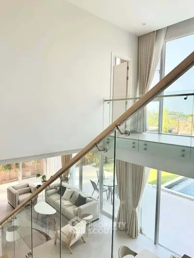 Luxurious modern living room with glass staircase and pool view, perfect for elegant living.