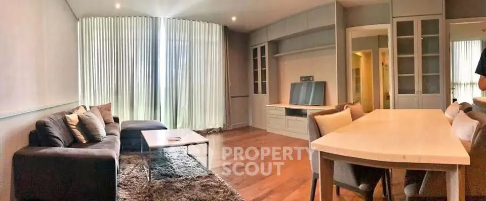 Spacious living room with modern decor and ample natural light, featuring a cozy seating area and elegant dining space.