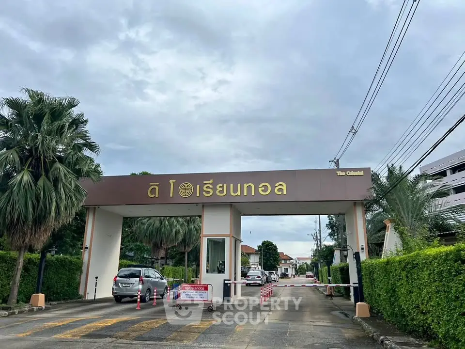 Elegant gated entrance of a residential community with lush greenery and security features.