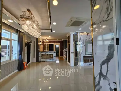 Luxurious open-plan living area with marble accents and elegant chandeliers in a modern home.