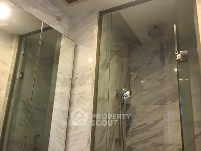 Luxurious marble bathroom with glass shower enclosure and modern fixtures.