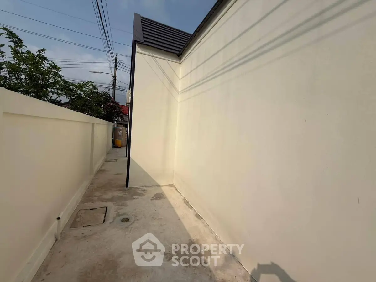 Narrow exterior walkway with high walls and concrete flooring