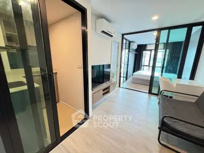 Modern apartment interior with open layout, featuring a cozy living area and a glimpse of the bedroom.