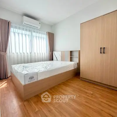 Modern bedroom with wooden flooring, large window, and sleek wardrobe design.