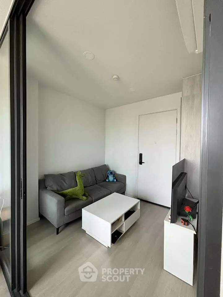 Modern living room with sleek furniture and minimalist design, featuring a cozy sofa and entertainment setup.