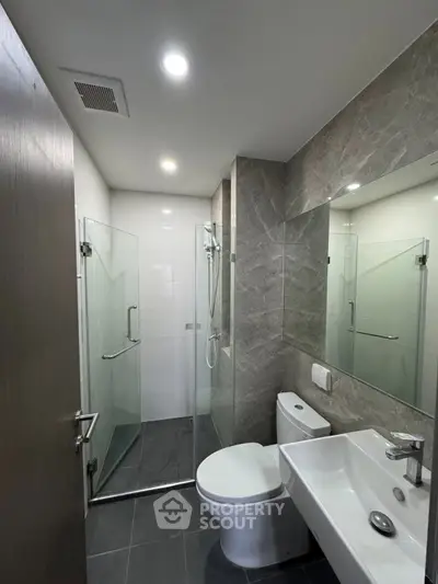 Modern bathroom with glass shower and sleek fixtures in contemporary apartment.
