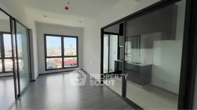 Modern apartment with glass doors and city view, featuring sleek kitchen and spacious living area.