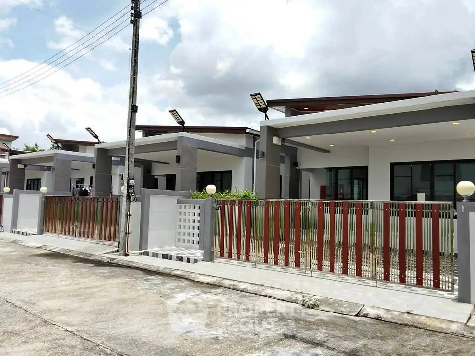 Modern single-story homes with sleek design and gated front yards under a cloudy sky.