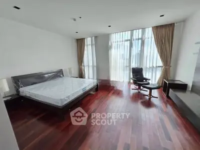 Spacious bedroom with hardwood floors and large windows in modern apartment