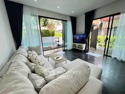 Spacious living room with pool view and modern decor, perfect for relaxation and entertainment.