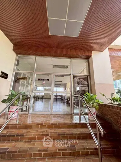 Elegant library entrance with brick steps and glass doors in a modern building.