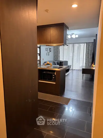 Modern open layout kitchen and living room with sleek dark flooring and stylish decor.