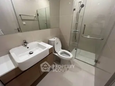 Modern bathroom with sleek fixtures and glass shower enclosure in contemporary apartment.