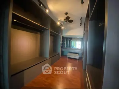Spacious walk-in closet with wooden flooring and ample storage space.