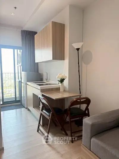 Modern compact kitchen with dining area and balcony view in stylish apartment