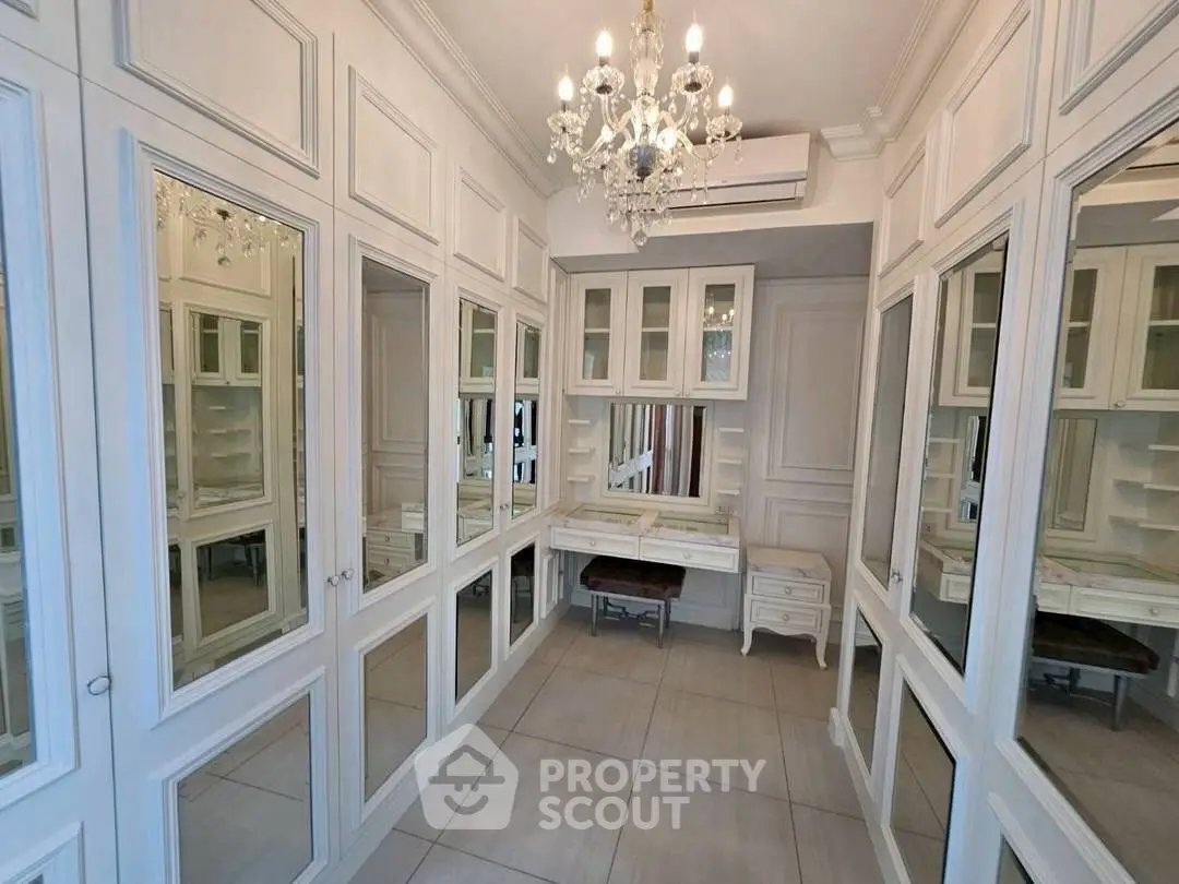 Luxurious walk-in closet with mirrored cabinets and elegant chandelier lighting.