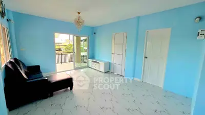 Spacious living room with blue walls, chandelier, and balcony access in modern home.