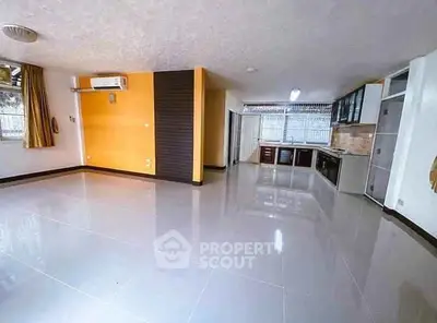 Spacious open-plan living area with modern kitchen and large windows.