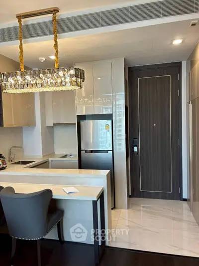 Luxurious modern kitchen with elegant chandelier and sleek cabinetry in high-end apartment.