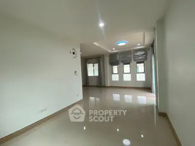 Spacious empty living room with large windows and glossy tiled floors in modern apartment.