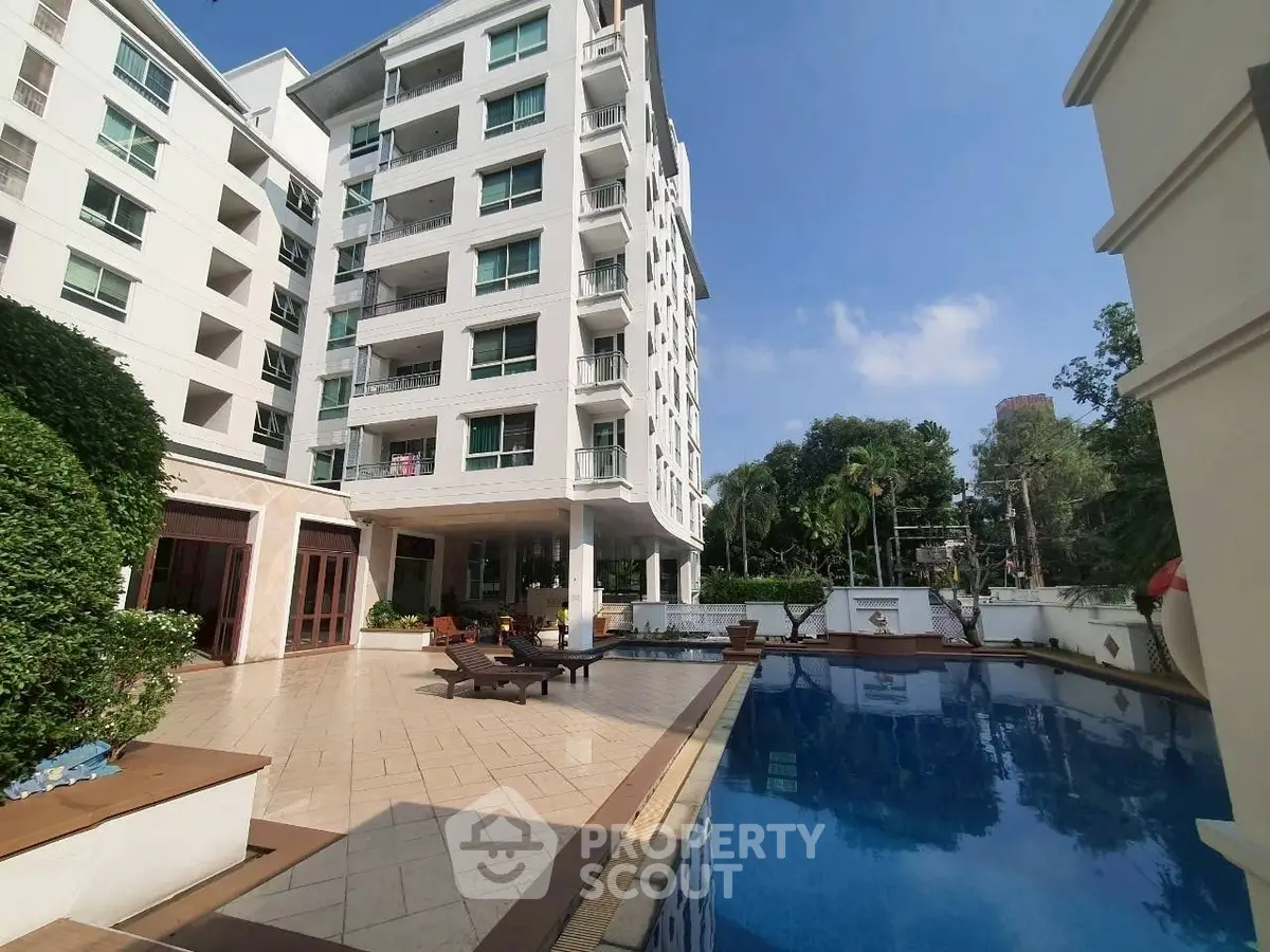 Luxurious apartment building with pool and lush greenery, perfect for modern living.