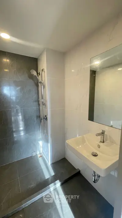 Modern bathroom with sleek shower and elegant sink in a stylish real estate property.