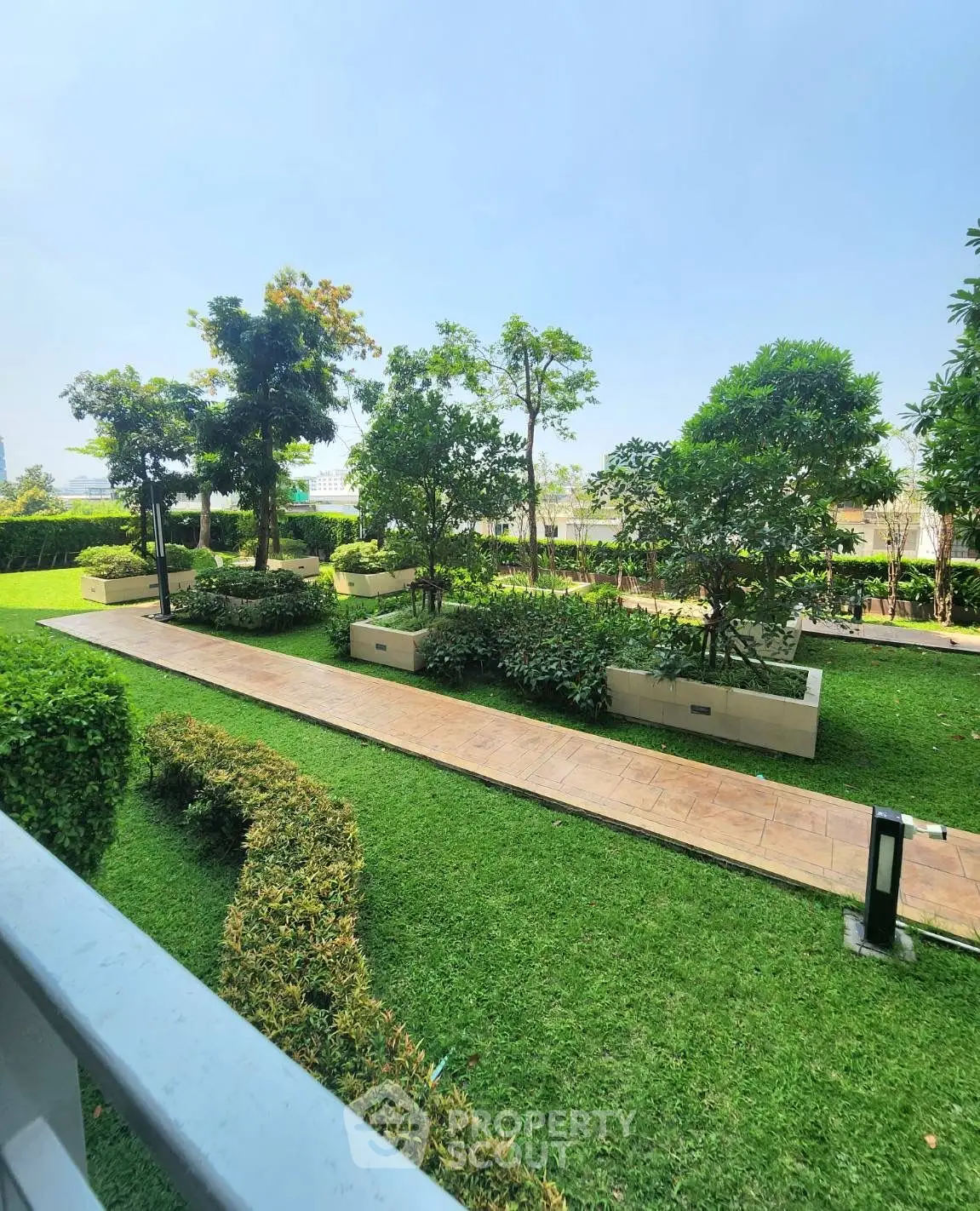Lush green garden with paved walkway in modern residential complex