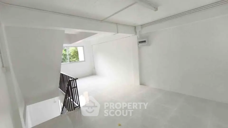 Spacious white interior with large window and staircase, ideal for modern living.