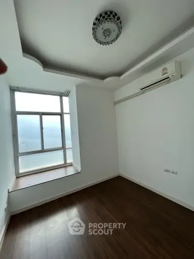 Spacious empty room with large window and air conditioning unit, ideal for customization.