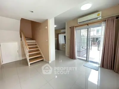 Spacious modern living room with staircase and sliding glass doors to balcony