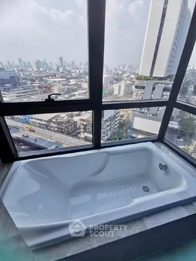 Luxurious bathtub with stunning cityscape view from high-rise apartment window.