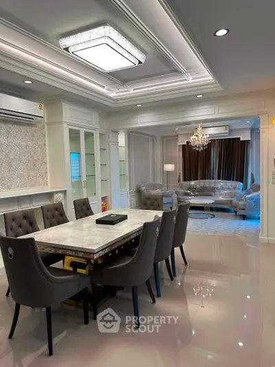 Luxurious open-plan living and dining area with elegant chandelier and plush seating.
