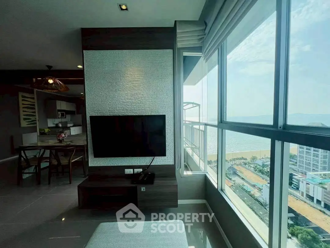 Modern living room with large windows offering stunning ocean view and stylish decor.