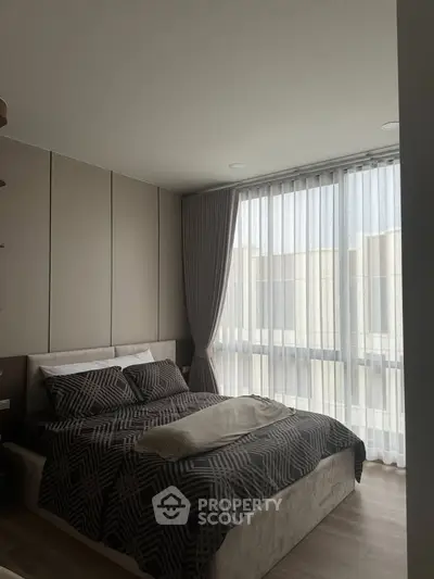 Modern bedroom with large windows and stylish decor in a contemporary apartment.