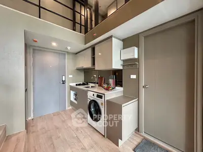 Modern loft apartment with sleek kitchen and washing machine, featuring open layout and stylish design.