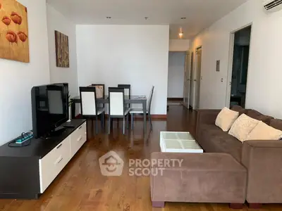 Spacious living room with modern decor and wooden flooring, featuring a cozy sofa and dining area.