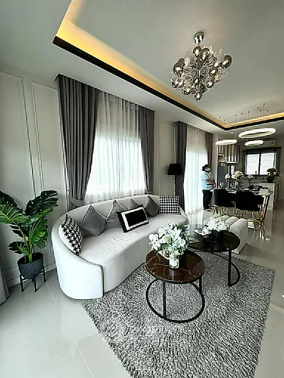 Luxurious modern living room with elegant decor and open kitchen layout, featuring chic lighting and plush furnishings.